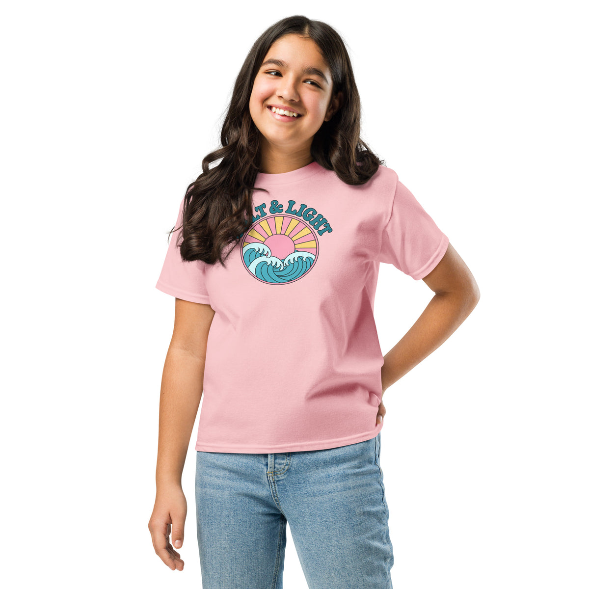 Girl wearing a light pink “Salt & Light” Christian T-shirt with teal lettering, ocean waves, and a yellow sunburst