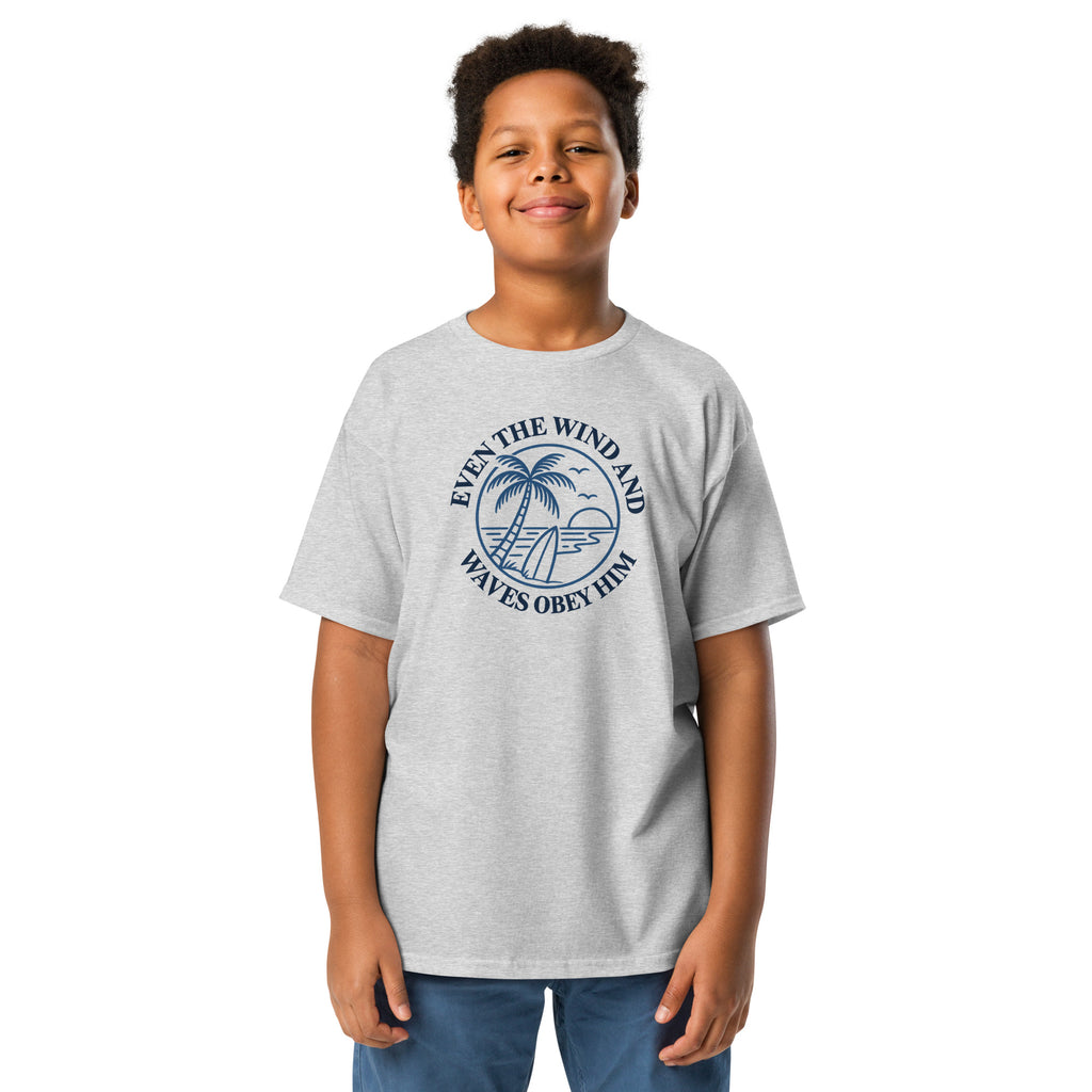 Grey Christian T-shirt with a navy palm tree, surfboard, and ocean graphic surrounded by “Even the wind and waves obey Him
